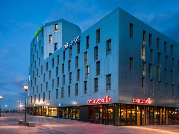 A modern hotel with a flat facade, multiple windows, and two Courtepaille restaurant signs. - ibis budget Mulhouse Centre Gare (Mulhouse)