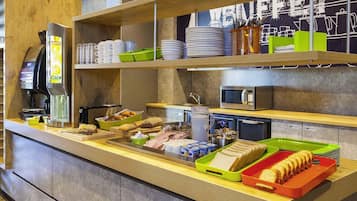 A buffet counter with various food items, a coffee machine, and a microwave.