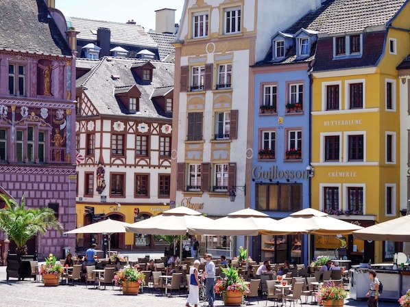 A European-style café with outdoor seating, a sign for 'Guillomé,' and traditional architecture. - ibis budget Mulhouse Centre Gare (Mulhouse)