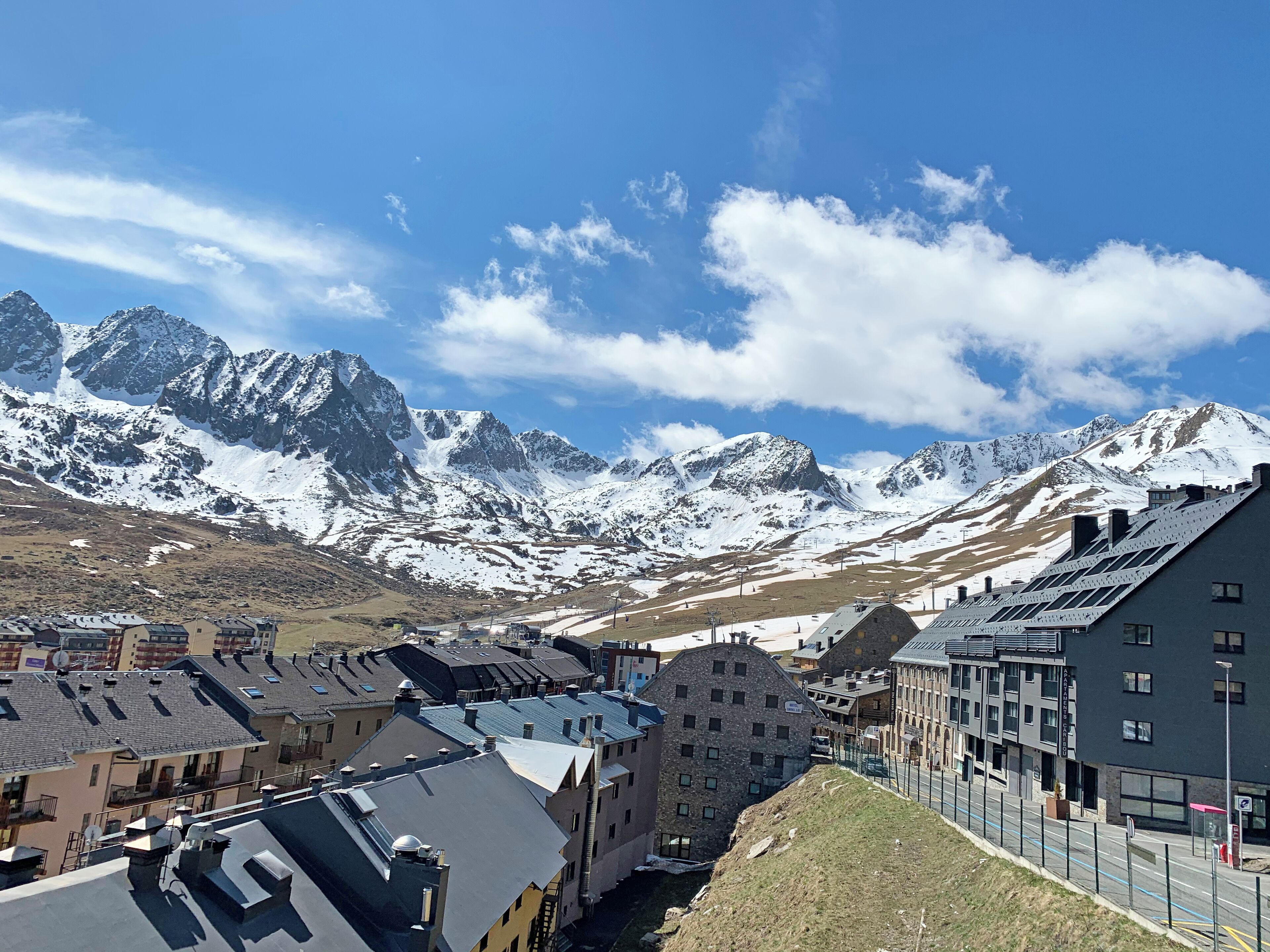Paisagem montanhosa com picos nevados e uma cidade com edifícios tradicionais.