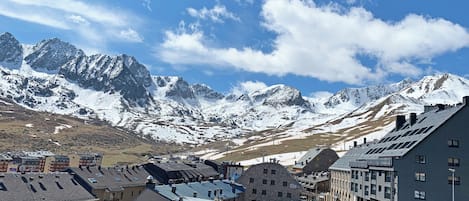 A mountainous landscape with snow-capped peaks and a town with traditional buildings.