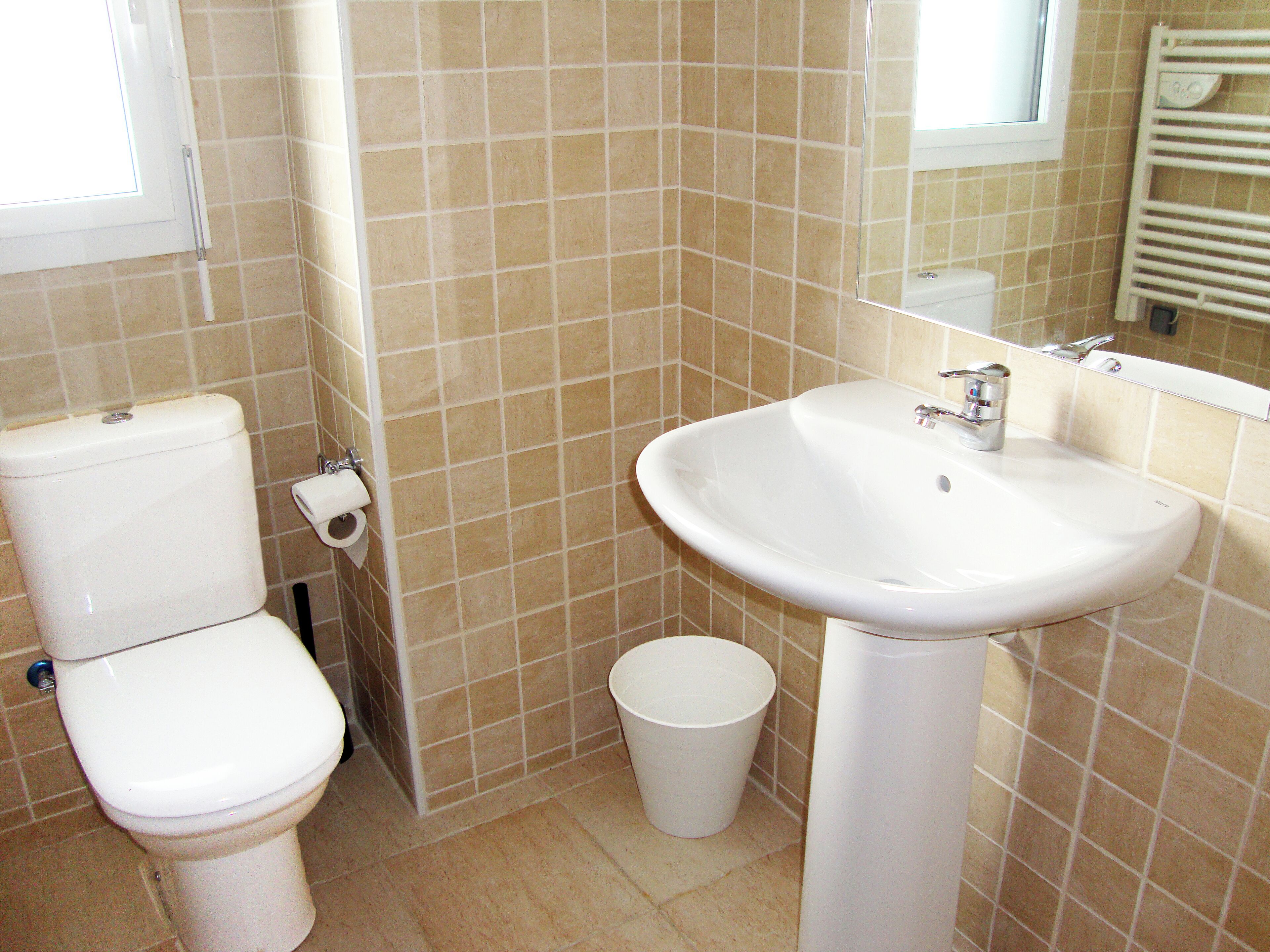 Un baño con inodoro, lavamanos y un pequeño cubo de basura.