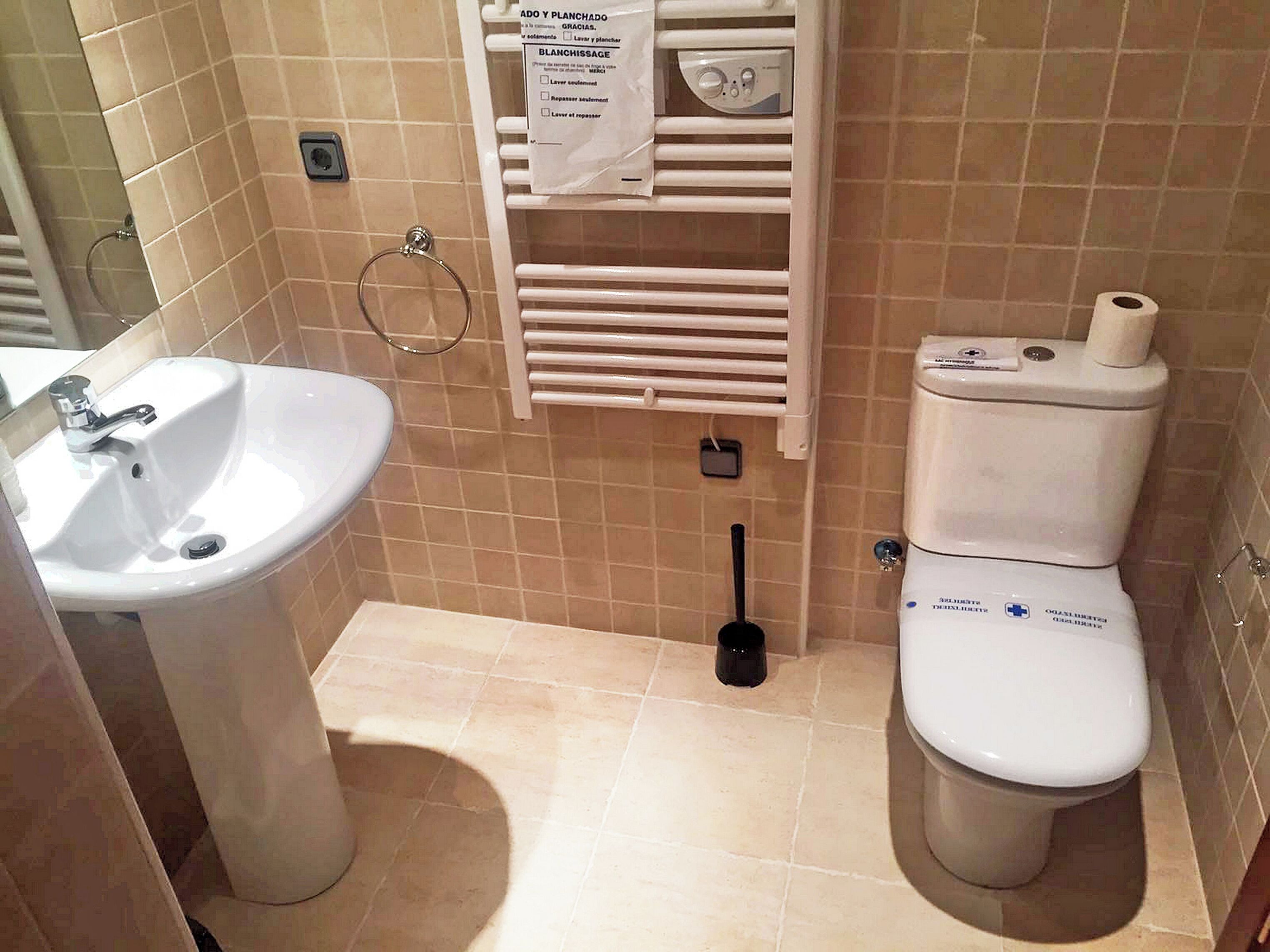 A bathroom with a sink, toilet, and towel rack.