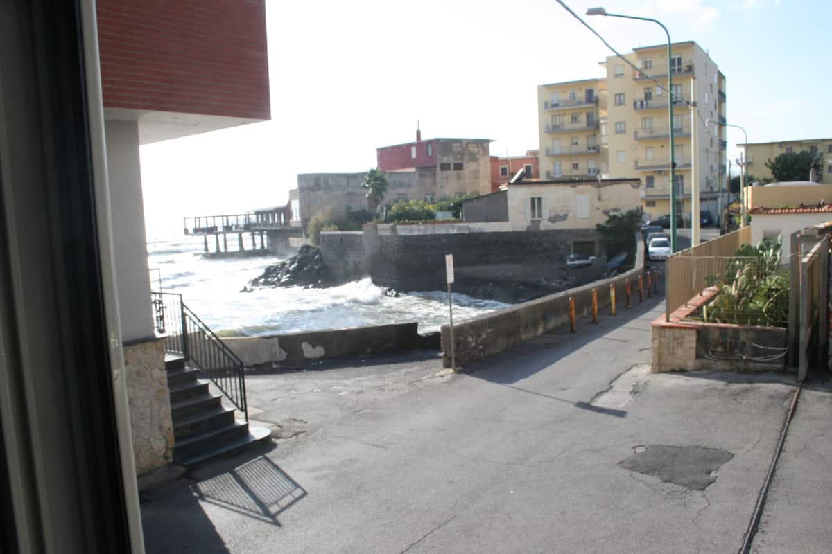 A coastal urban scene with a view of the sea, a pier, and buildings.