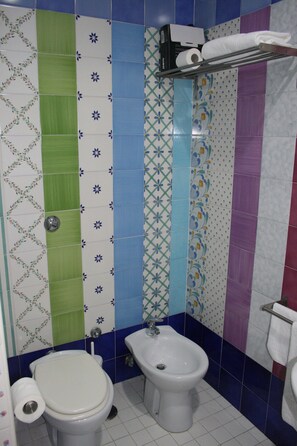 Un baño con inodoro, bidé y una repisa con una toalla.