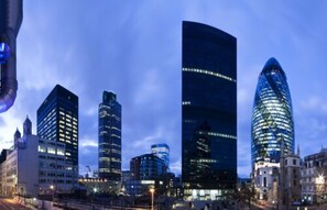 Un paysage urbain avec des gratte-ciel modernes, dont un bâtiment remarquable à la forme incurvée et à la façade en verre réfléchissant.