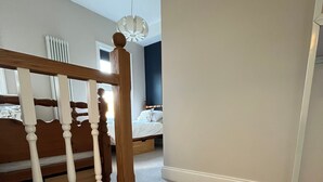 A staircase leading to a bedroom with a bed, a radiator, and a ceiling light fixture. - Hotel 50 (Bournemouth)