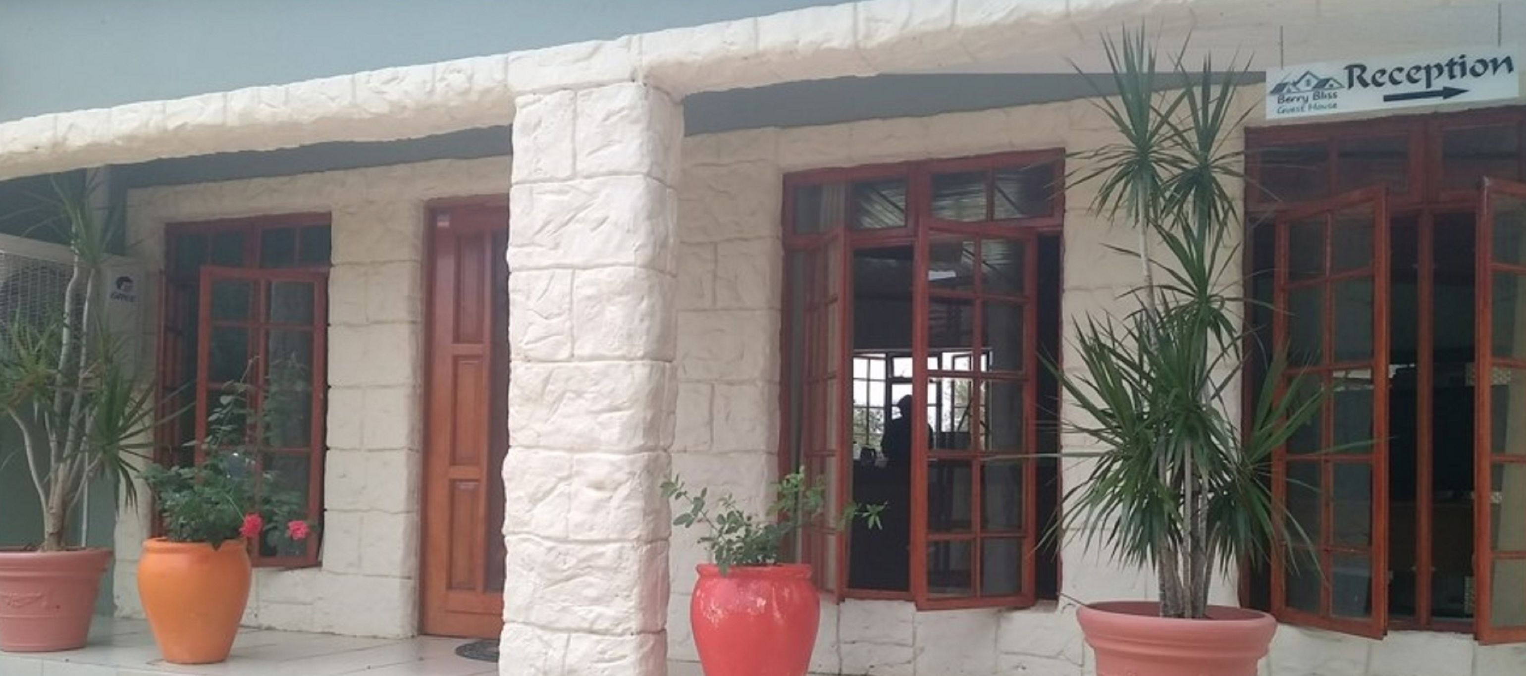A building with a reception sign, large windows, and potted plants.