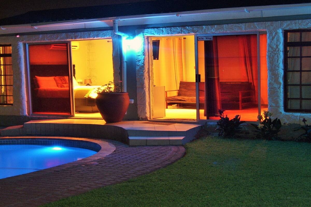 A house with a swimming pool, a patio, and a large window.