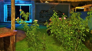 A thatched-roof structure with a stone wall and a sign reading "Berry Guest." - Berry Bliss Guest House (Gaborone)