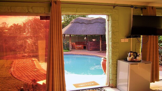 A room with a pool, a television, and a welcome mat. - Berry Bliss Guest House (Gaborone)
