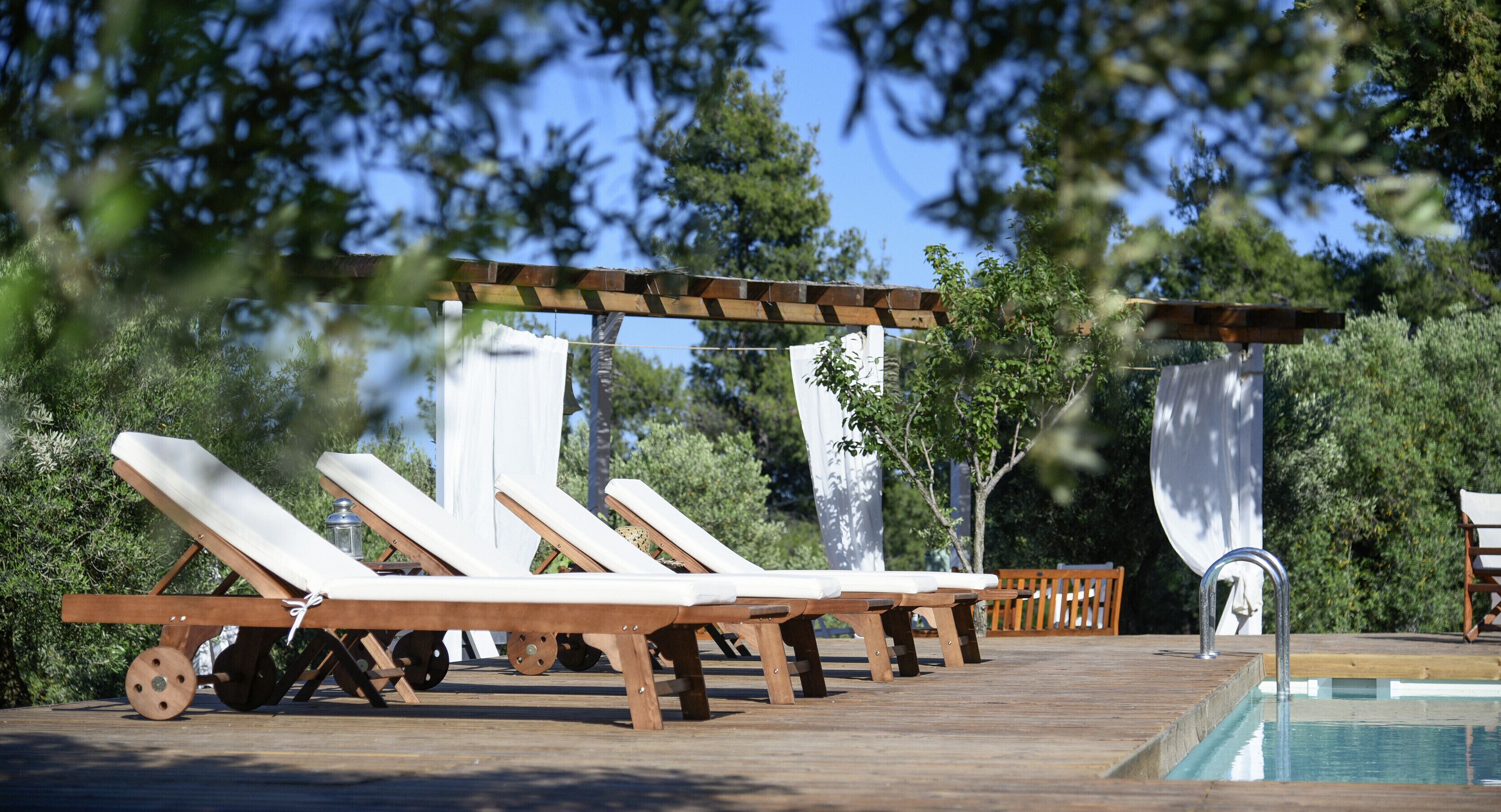 Una terraza de madera con sillones de descanso y una piscina.
