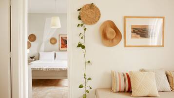 Un dormitorio con una cama, almohadas, una planta colgante y adornos en la pared.