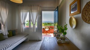 A room with a bed, a table with a plant, a picture frame, and a view of the outdoors. - Kopana Resort (Kassandra)