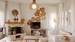 A cozy living room with a fireplace, a television, a bookshelf, and a comfortable sofa. - Kopana Resort (Kassandra)