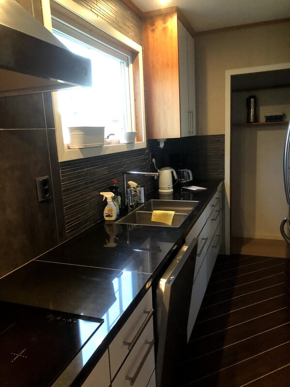 Una cocina moderna con encimera negra, electrodomésticos de acero inoxidable y una ventana que proporciona luz natural.