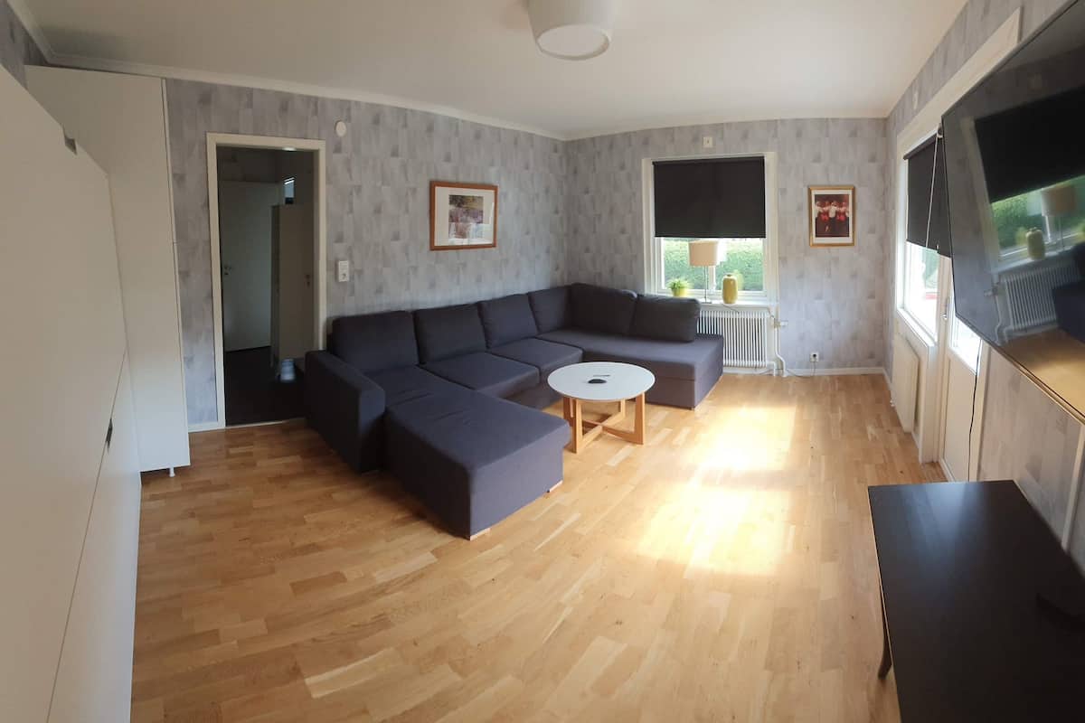 Ein Wohnzimmer mit einer Eckcouch, einem runden Couchtisch und einem Fernseher.
