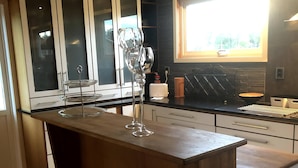 A modern kitchen with a central island, dark flooring, and a window providing natural light. - Gävle Pendlarlägenhet (Gävle)