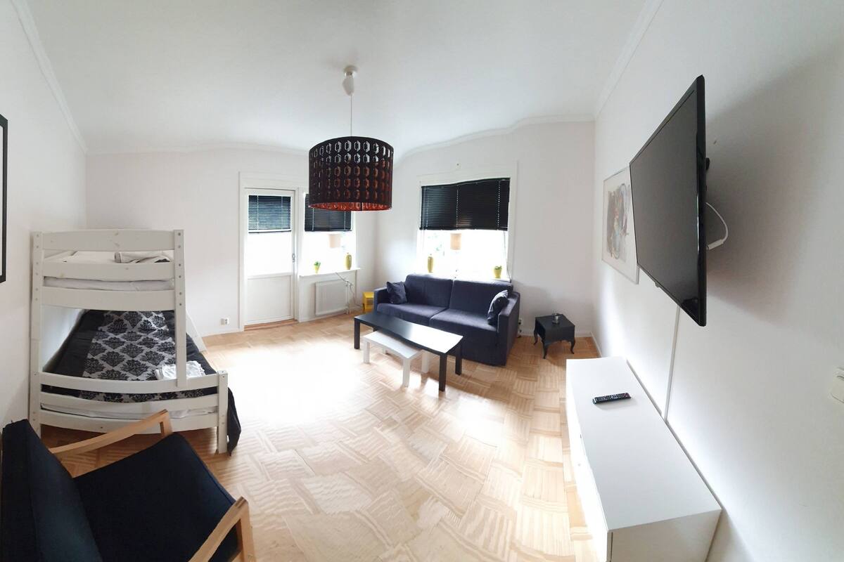 Ein Zimmer mit einem Etagenbett, einer Schlafcouch, einem Fernseher und einem gerahmten Bild an der Wand.