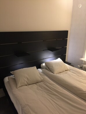 A room with two beds, each with a headboard and pillows. - Gävle Pendlarlägenhet (Gävle)