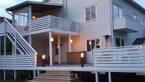 A modern multi-story house with a balcony, a staircase, and a porch area with lighting. - Gävle Pendlarlägenhet (Gävle)