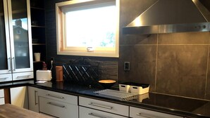 A modern kitchen with a window, stainless steel appliances, and a wooden countertop. - Gävle Pendlarlägenhet (Gävle)