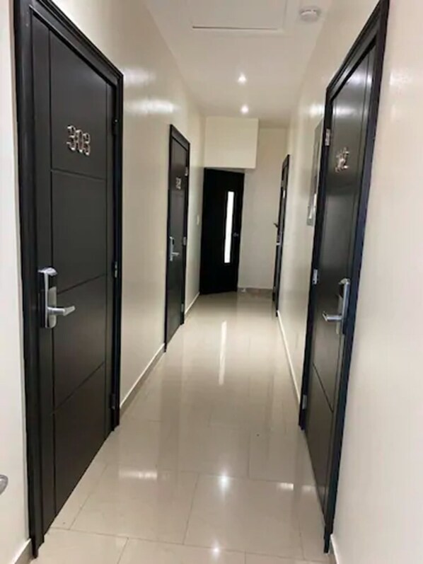 Un pasillo con puertas negras, cada una marcada con un número.
