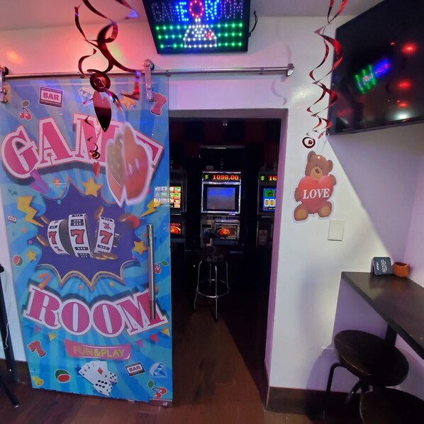 A room with a 'Candy Room' sign, slot machines, a teddy bear decoration, and a 'Love' sign on the wall.