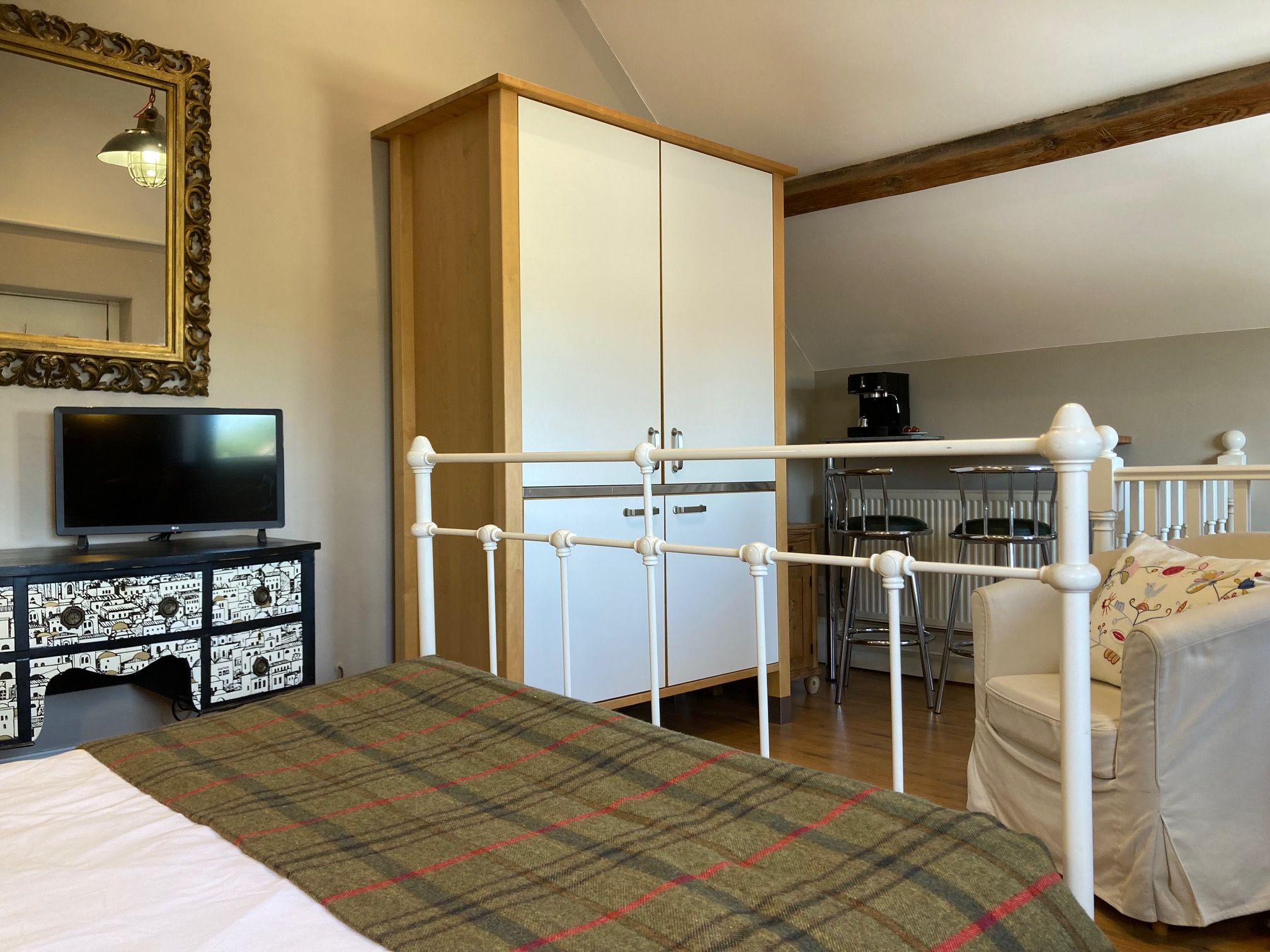 Ein Schlafzimmer mit einem Bett, einem Fernseher auf einem Schrank, einem Kleiderschrank und einer Kaffeemaschine.