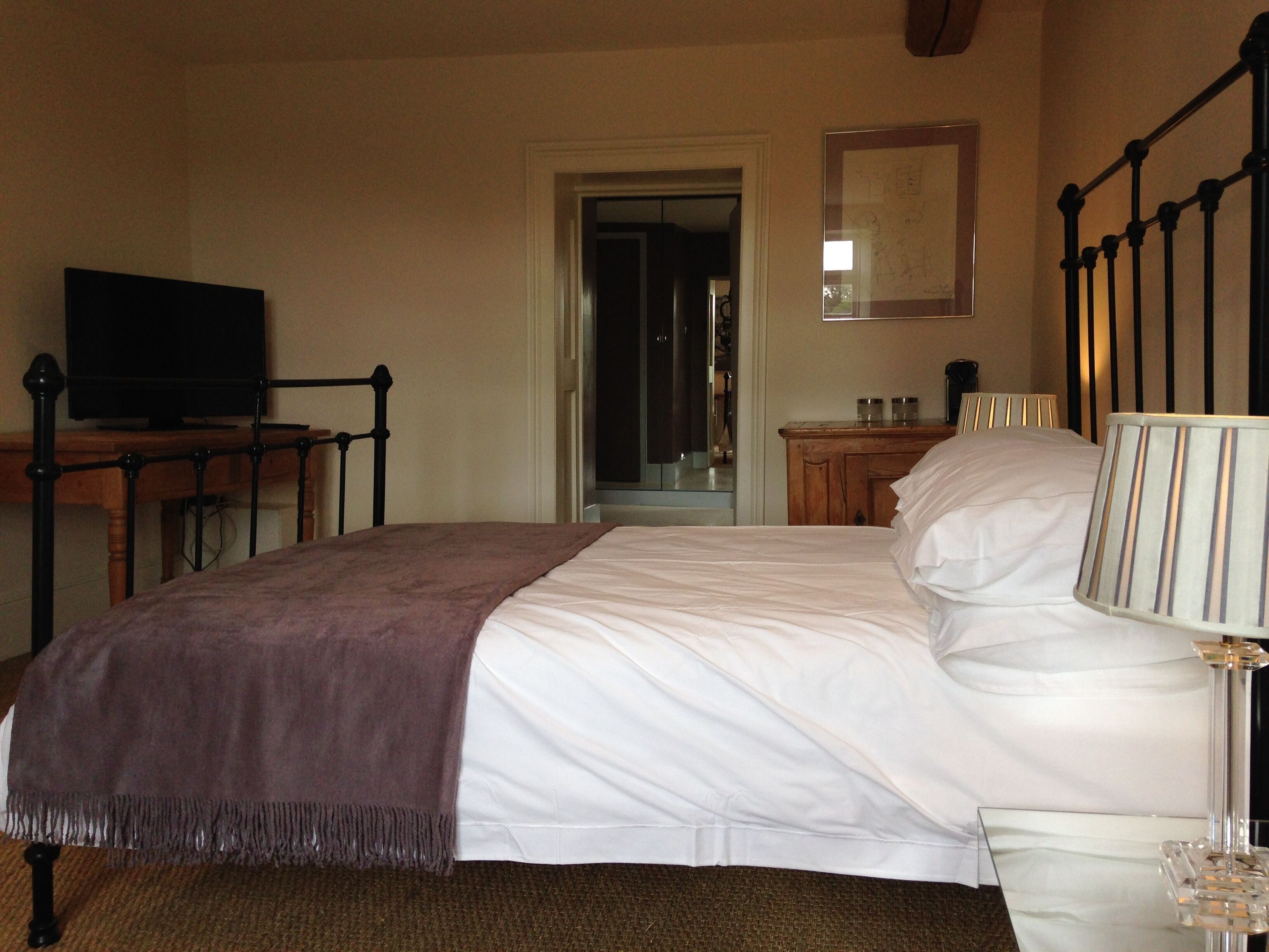 A bedroom with a bed, a television, a bedside table, and a mirror.
