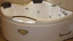 A large, white, freestanding bathtub with a built-in seat and a small window above it. - Saul Farm (Gloucester)