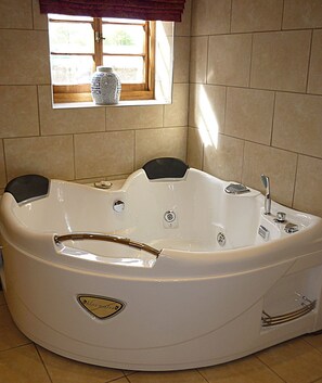 A large, white, freestanding bathtub with a built-in seat and a small window above it. - Saul Farm (Gloucester)
