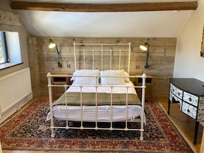 Un dormitorio con cama con dosel, dos lámparas de noche, un radiador, un tapete estampado y una mesita de noche con una lámpara decorativa.