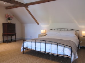 A bedroom with a metal bed frame, a wooden dresser, and a nightstand with a lamp.