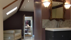 A modern bathroom with a large mirror, a vanity, and a seating area with a chair. - Saul Farm (Gloucester)