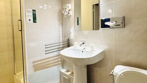 Ein Badezimmer mit Waschbecken, Spiegel, Handtuchspender und Duschbereich.