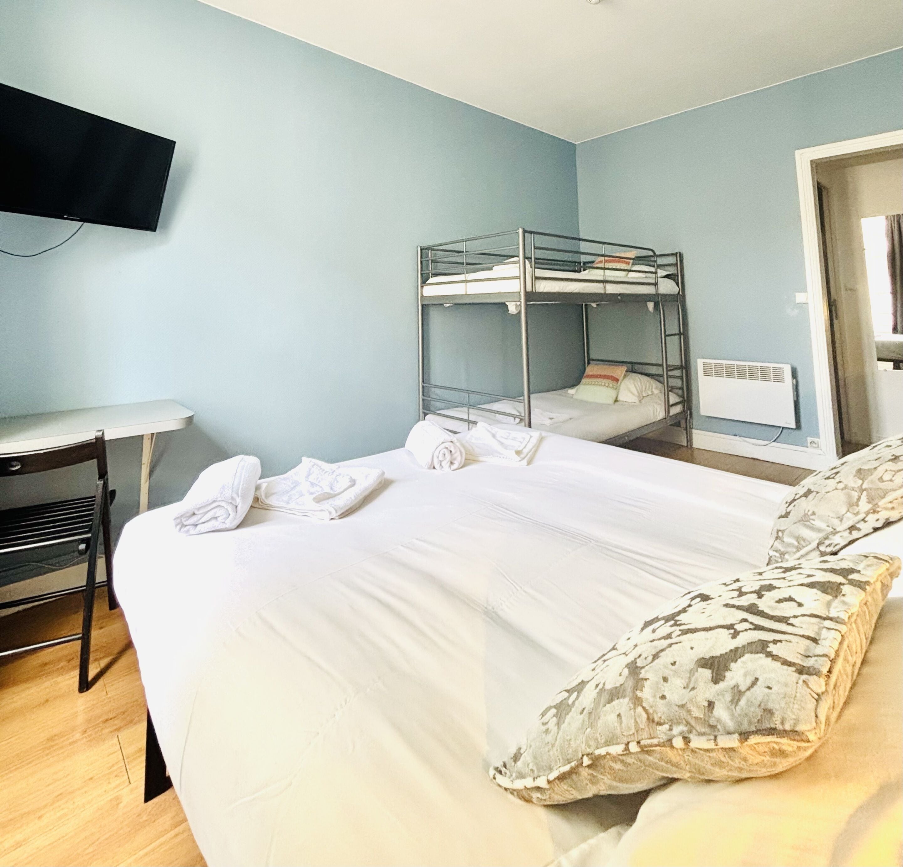 Een kamer met stapelbedden, een bureau, een stoel en een aan de muur bevestigde televisie.