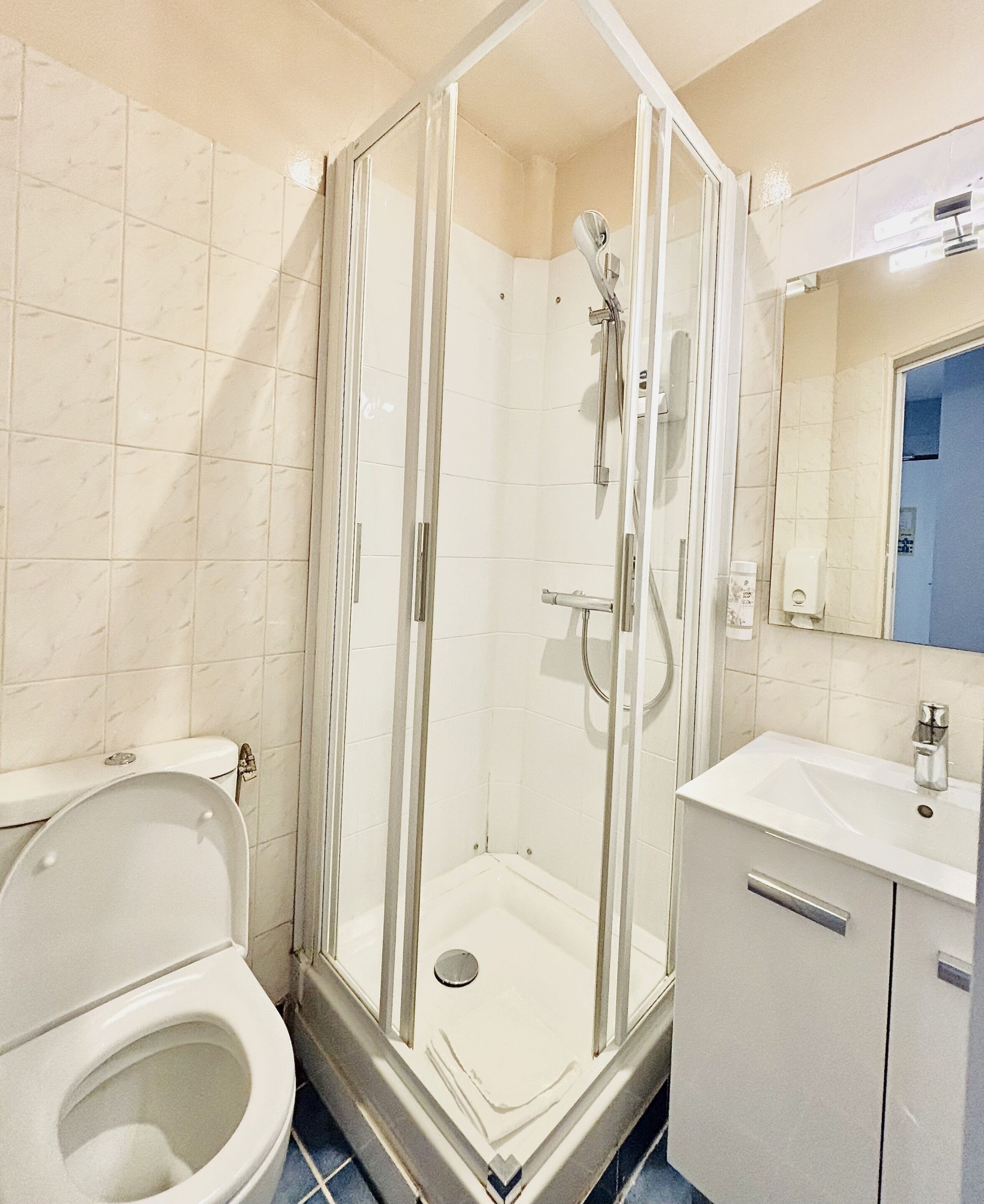 A bathroom with a shower enclosure, toilet, sink, and mirror.