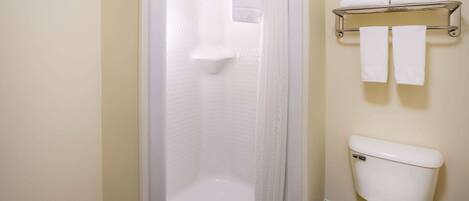 A bathroom with a bathtub, toilet, and a towel rack with towels.