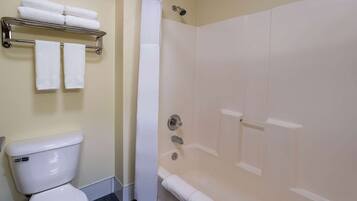 A bathroom with a toilet, a shower with a glass door, and a towel rack with folded towels.