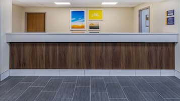 Un'area reception con scrivania in legno, quadri appesi alle pareti e pavimento piastrellato.