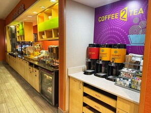 A coffee and tea station with dispensers labeled 'HOT H2O', 'GOURMET', and 'COFFEE 2 TEA'. There are also yogurt and milk dispensers, and a refrigerator with a glass door. - Home2 Suites by Hilton Austin Airport (Austin)