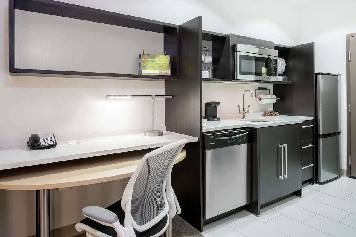 A modern kitchen with a built-in microwave, coffee maker, and dishwasher.
