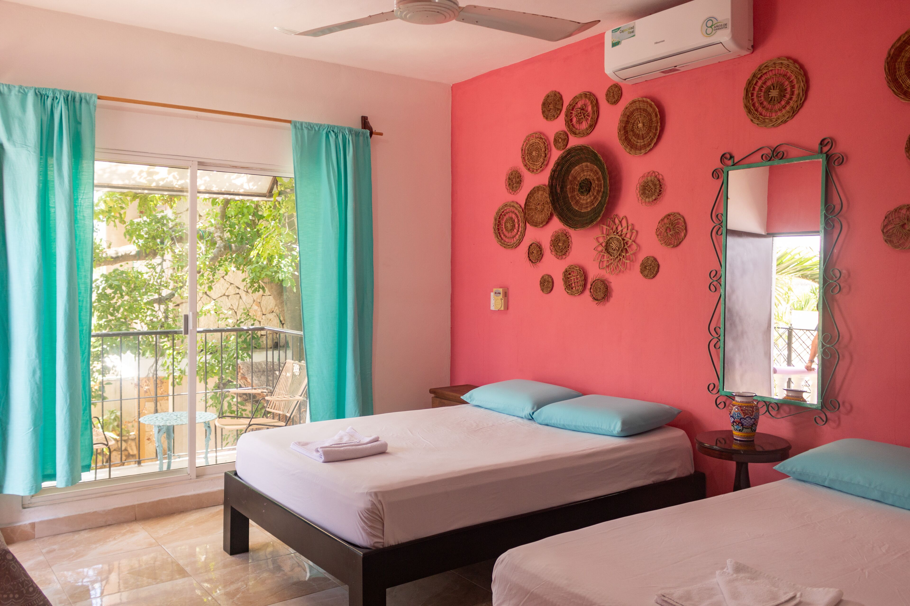 Une chambre d’hôtel avec deux lits, un balcon doté d’une table et de chaises, et des éléments décoratifs fixés aux murs.