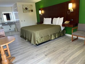 A hotel room with a bed, bedside table, chair, and a small dining table.