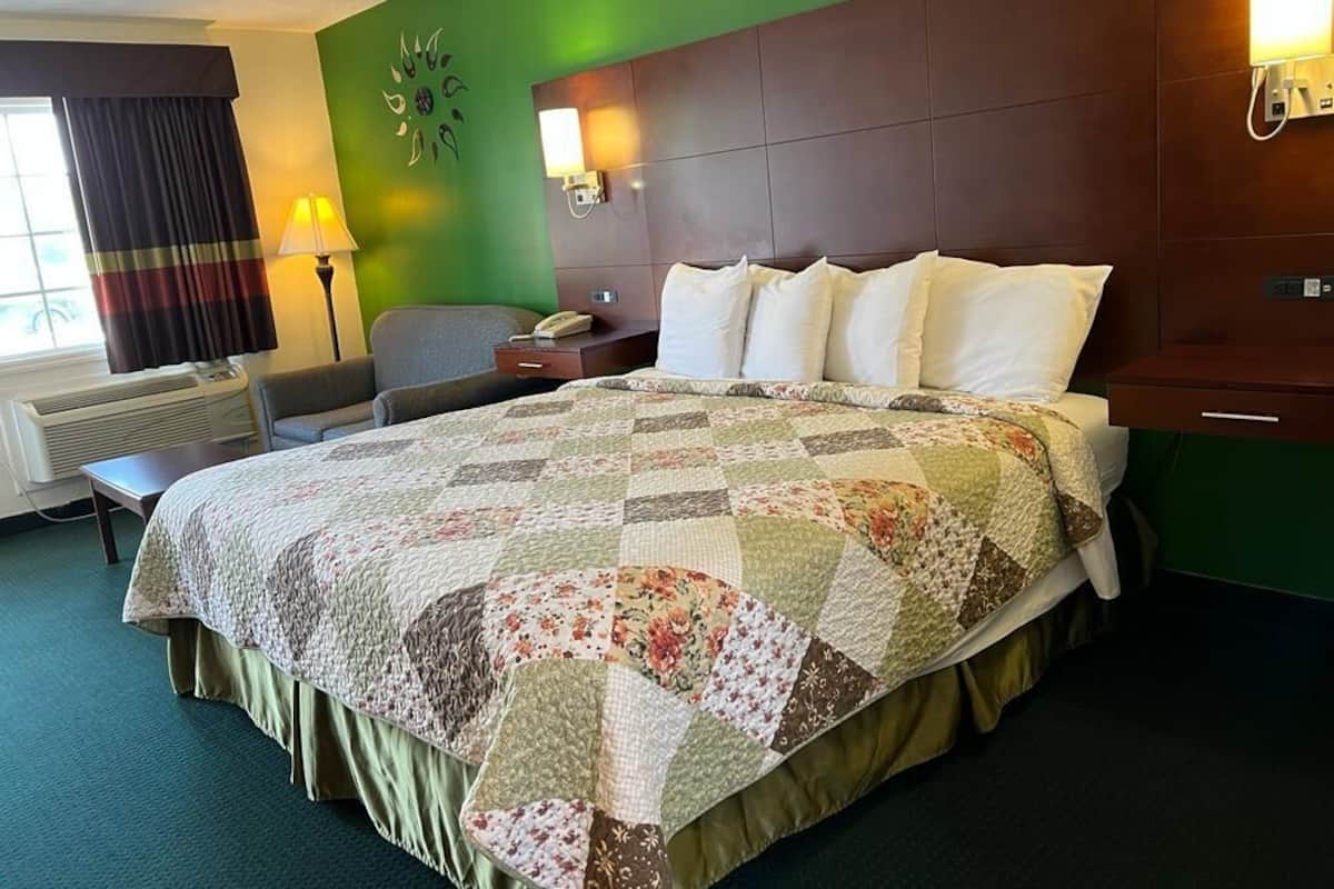 Une chambre d’hôtel avec un grand lit, un bureau, une chaise, une lampe et un téléphone fixé au mur.