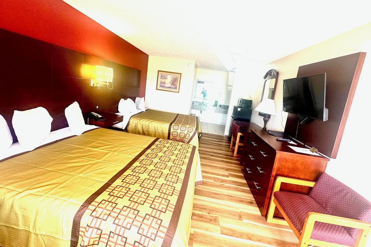 Une chambre d’hôtel avec deux lits, une télévision, un bureau et une chaise.