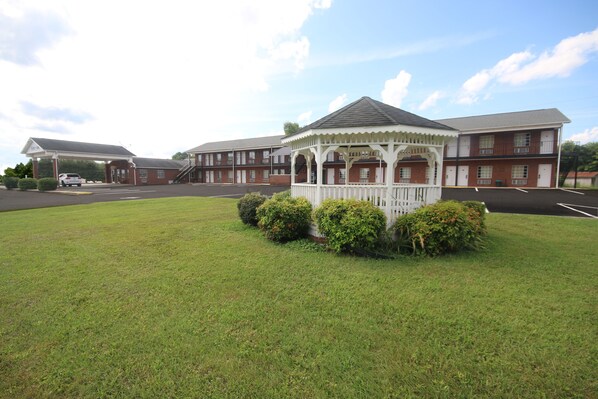 A gazebo in a grassy area with a building in the background.