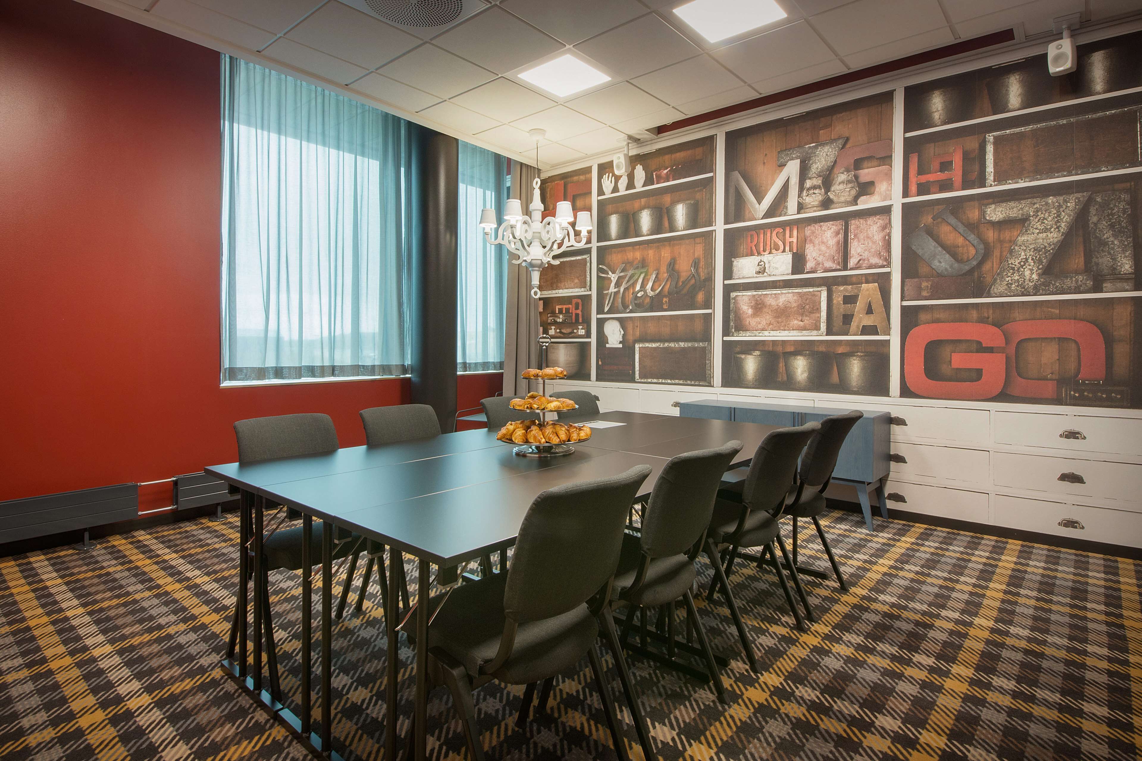 A conference room with a large table, chairs, a chandelier, and a wall with decorative letters and objects.