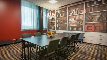 A conference room with a large table, chairs, a chandelier, and a wall with decorative letters and objects.